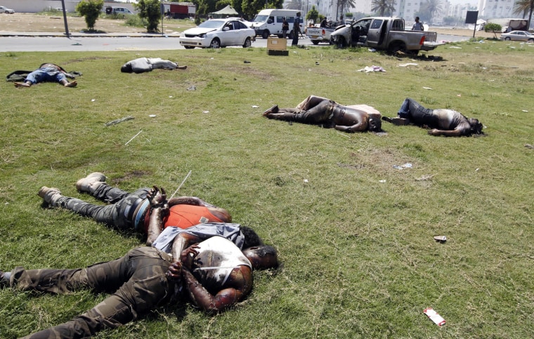 Image: Bodies are seen on a street at a military encampment in Tripoli