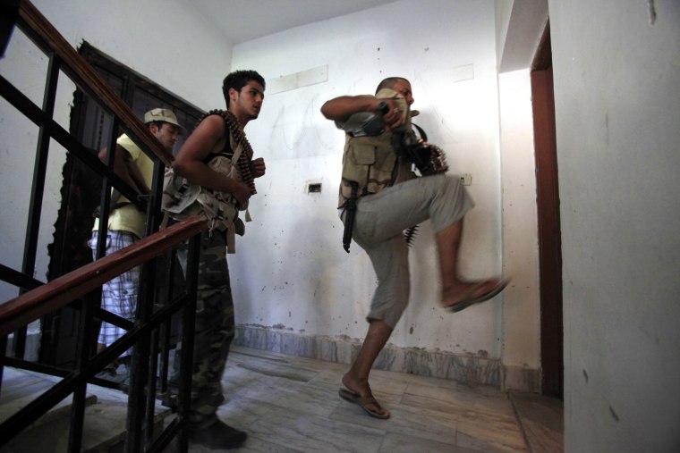 Image: A Libyan rebel fighter kicks down a door during a house search for snipers in the final push to flush out Moammar Gaddafi's forces in Abu Slim