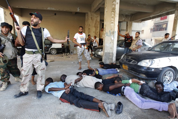 Image: Libyan rebel fighters stand guard over detainees during a fight for the final push to flush out Muammar Gaddafi's forces in Abu Salim district in Tripoli