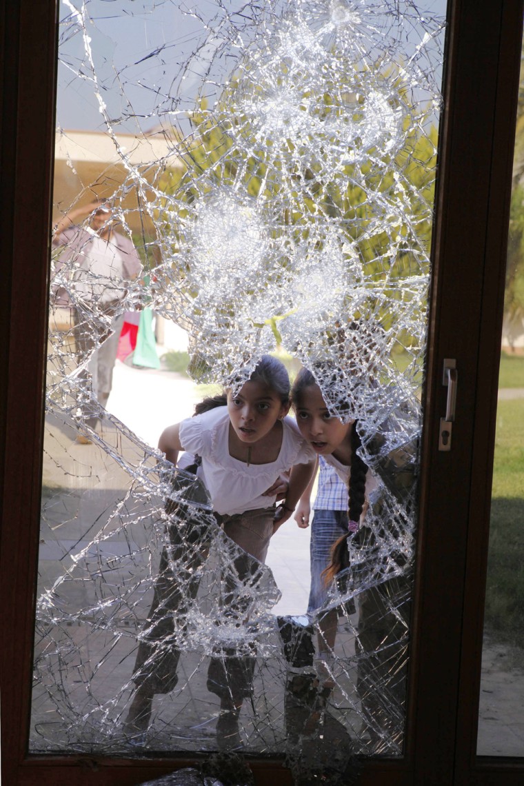 Image: Libyan girls look through a shattered glass door at Aisha Gaddafi's house in Bin Ashour in Tripoli