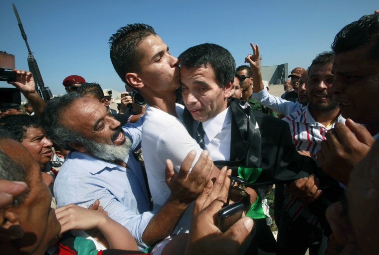 Libyan air force pilot Ali Al-Rabti is hugged by his son upon his arrival at Mitiga airport in Tripoli on Sept. 18, 2011. Two air force pilots who refused to bomb civilians during Gadhafi’s rule and fled to Malta in February returned to Tripoli.