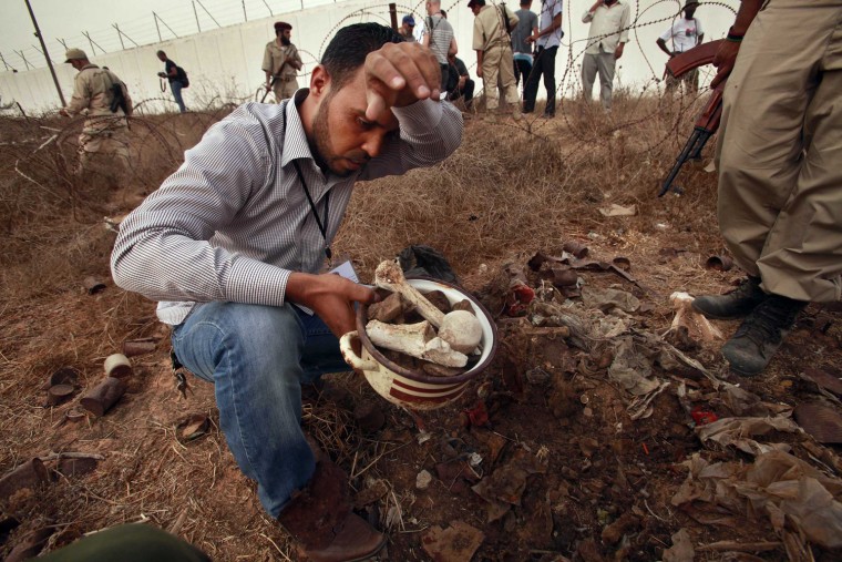 A man collected human remains at the site of a mass grave in Tripoli September 25, 2011. Libya's interim authorities said they had found a mass grave in the capital containing the bodies of more than 1,270 people killed by Gadhafi's security forces in a 1996 massacre at Tripoli's Abu Salim prison.