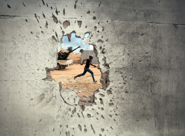 A Libyan revolutionary fighter runs for cover while attacking pro-Gadhafi forces in Sirte, on Oct. 7, 2011.