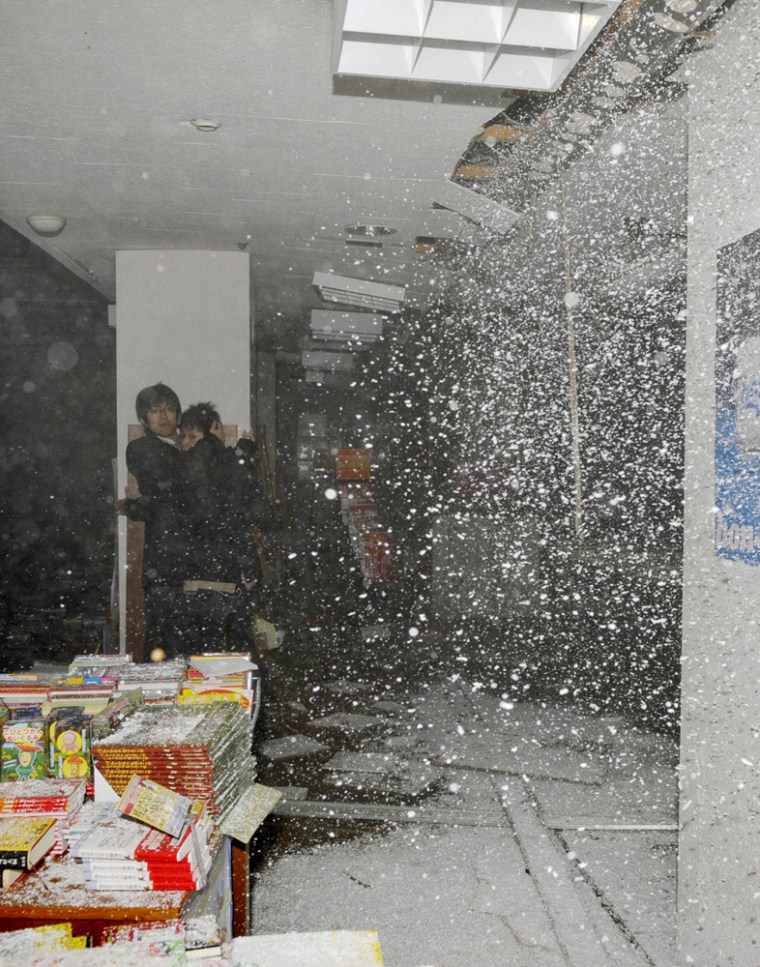 Image: People take shelter as a ceiling collapses in a bookstore during an earthquake in Sendai