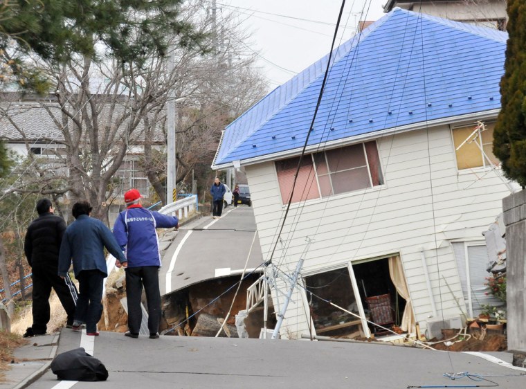Image: residents check the damaged done on a ro