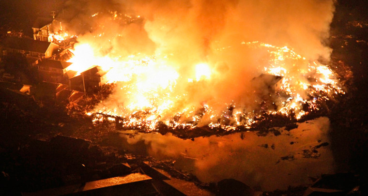 Image: Houses burn at night following an earthquake in Natori City in northeastern Japan.