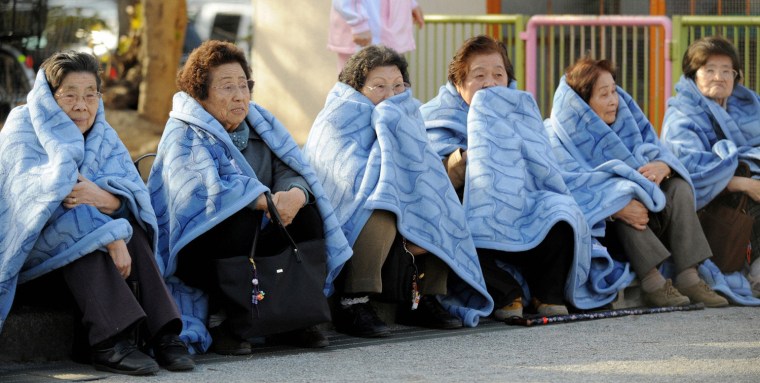 Image: Women wait on the street after evacuating a building following an earthquake in Tokyo