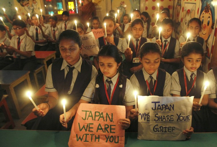Image: Students hold candles as they pray for Japan's earthquake victims inside their school in the western Indian city of Ahmedabad