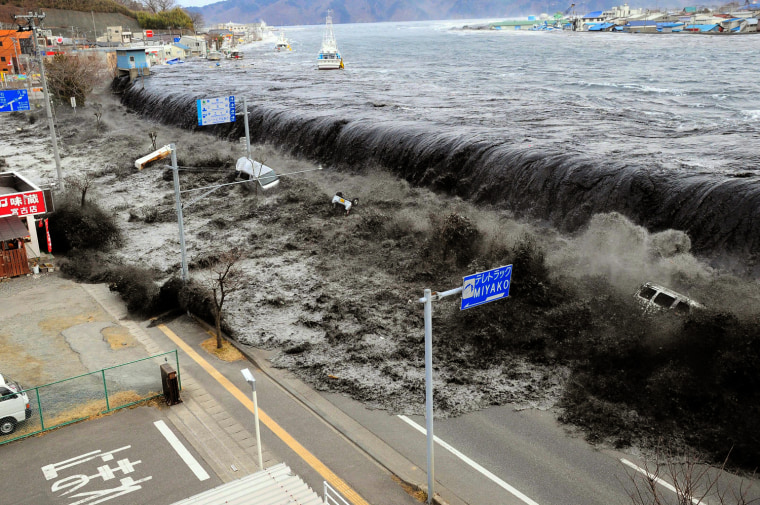 Image: Waves overwhelm a levee, swallowing a seaside village near the mouth of Hei River