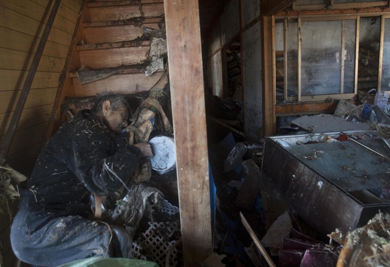 Image: A dead man lies on the stairs of a destroyed house in Sendai, northeastern Japan