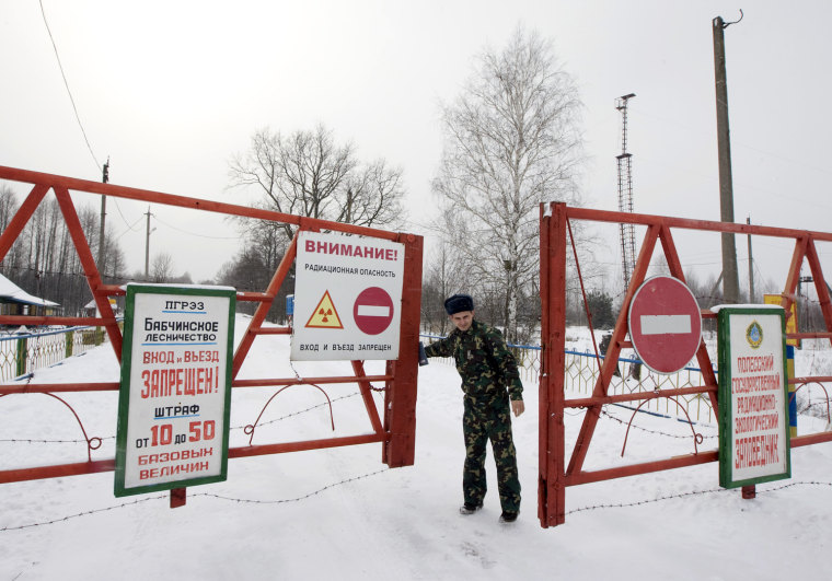 Image: A Belarussian guard opens the gate at the entrance to the state radiation ecology reserve near the village of Babchin