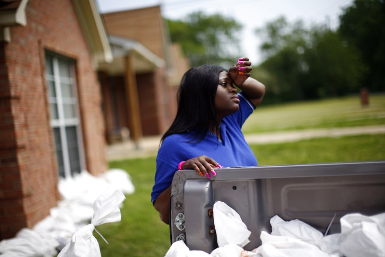 Image: Nailor pauses to wipe her forehead while using sandbags to protect a home as floodwaters slowly rise in Memphis