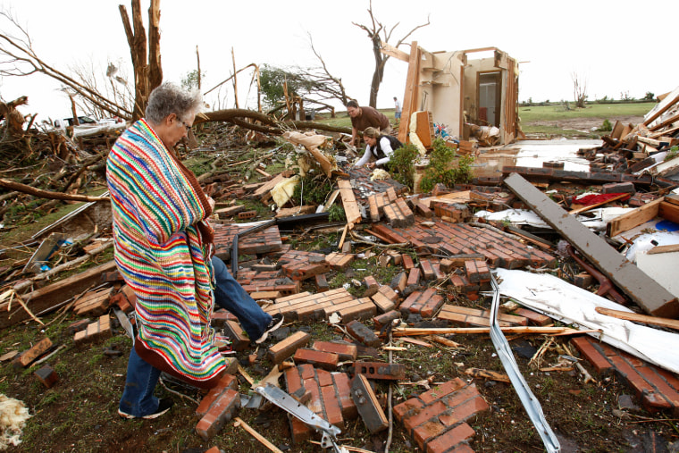 Image: Martha Gaines (L) walks among the rubble of her home after a tornado ripped through the Falcon Lake area of Piedmont