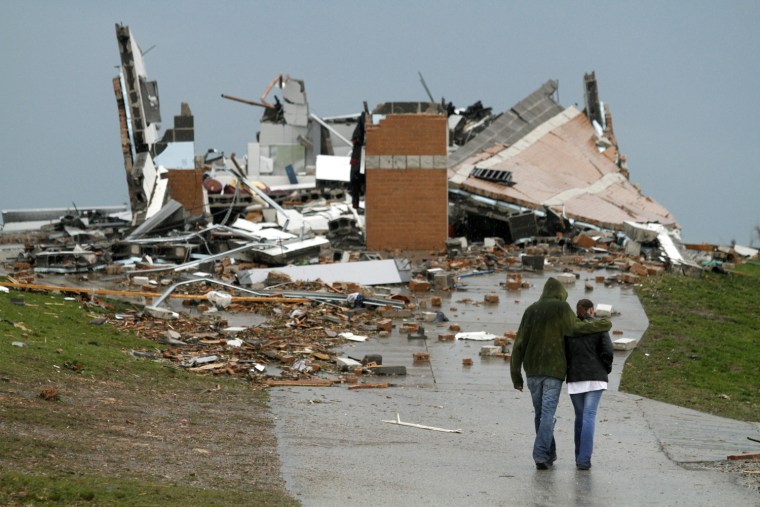 Image: A couple walk near a building destroyed by a tornado that hit Joplin