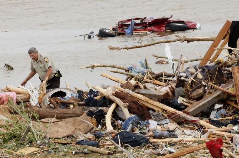 Image: An official searches for a missing child near the lake shore after a tornado ripped through the Falcon Lake area of Piedmont