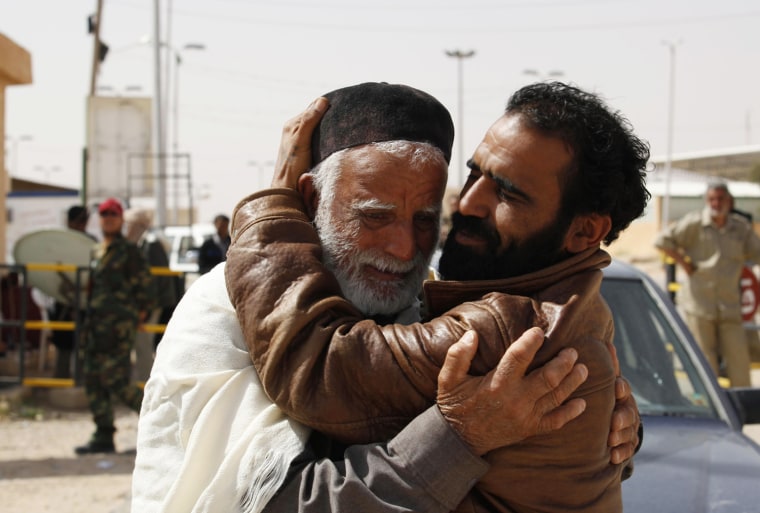 Image: A rebel fighter hugs a refugee fleeing unrest in Libya at the southern Libyan and Tunisian border crossing of Dehiba