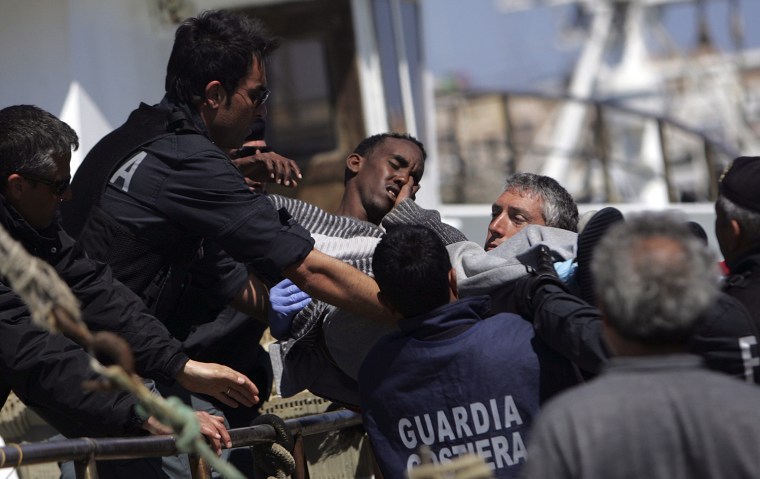 Image: Italian Police and Guardia Costiera officers carry an injured refugee as he arrives on the southern Italian island of Lampedusa