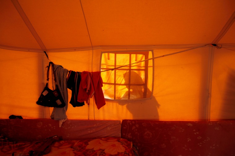 Image: Libyan refugee stands outside her tent at a refugee camp in Dehiba
