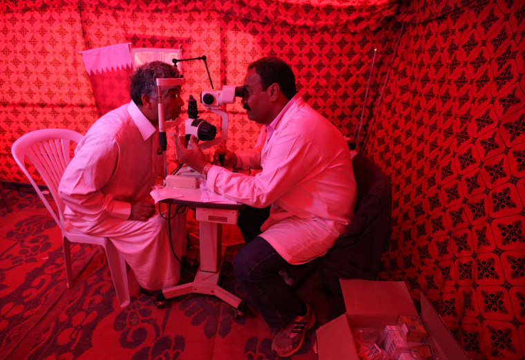Image: An ophthalmologist examines the eyes of a Libyan refugee in a makeshift hospital tent at a refugee camp in Tataouine