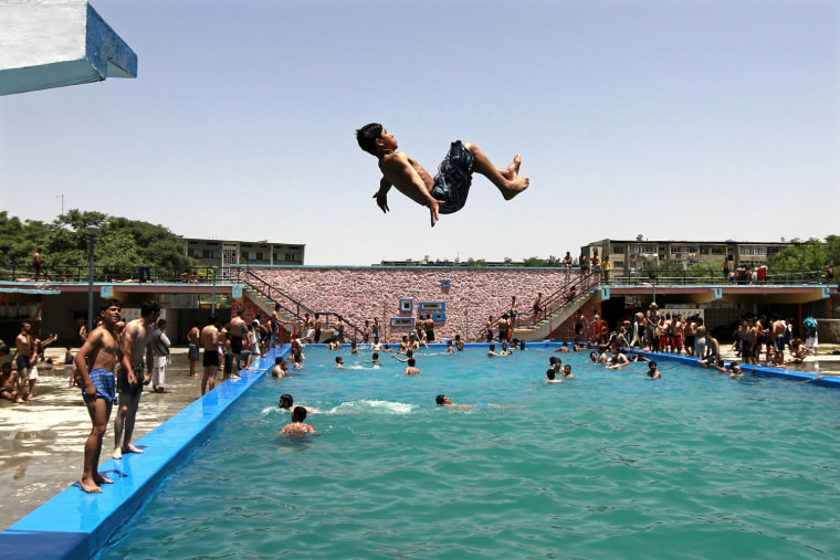 Image: An Afghan boy jumps into a public swimming pool in Kabul