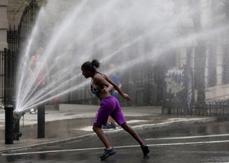 Image: A child plays under the spray of a fire hydrant in Riverside, Manhattan, as temperatures soared in New York
