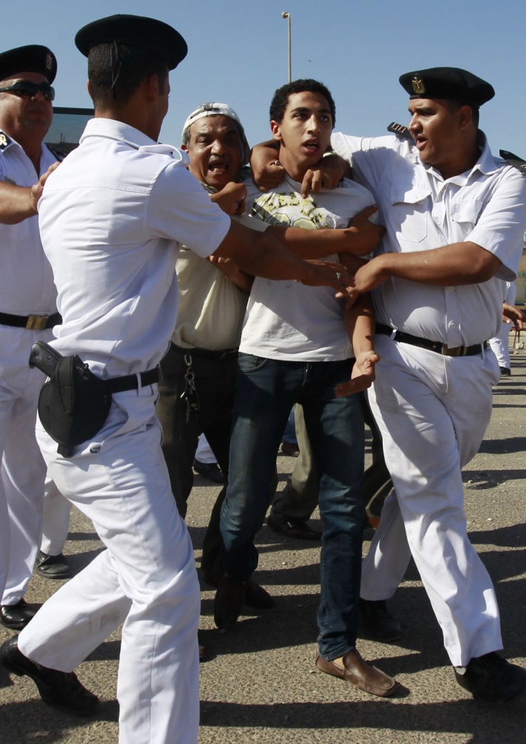 Image: A protester against Egypt's former President Mubarak is stopped by police officers during clashes in Cairo