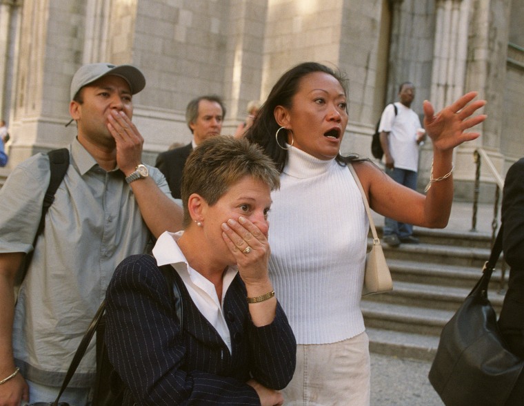People in front of New York's St. Patrick's Cathedral react with horror as they look down Fifth Ave towards the World Trade Center towers after planes crashed into their upper floors Tuesday morning, Sept. 11, 2001. Explosions and fires left gaping holes in the 110-story buildings and President Bush said the crashes were apparently the work of terrorists.  (AP Photo/Marty Lederhandler)