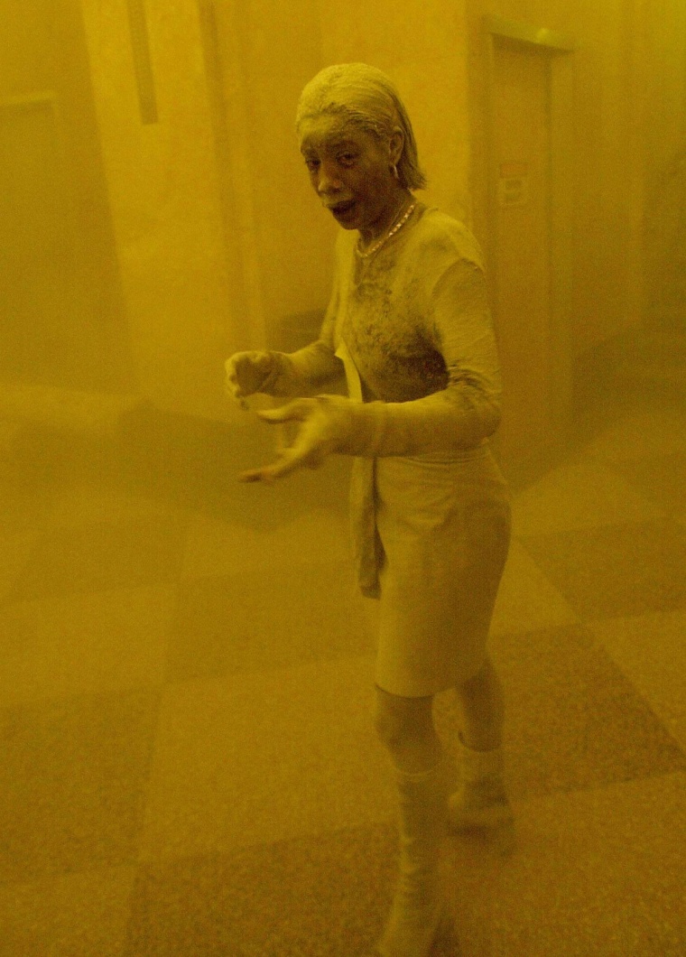 A woman covered in dust takes refuge in an office building after the top of one of the World Trade Center towers collapsed after two planes crashed into each building 11 September, 2001, in New York.  The woman was caught outside on the street as the cloud of smoke and dust enveloped the area.  AFP PHOTO/Stan HONDA