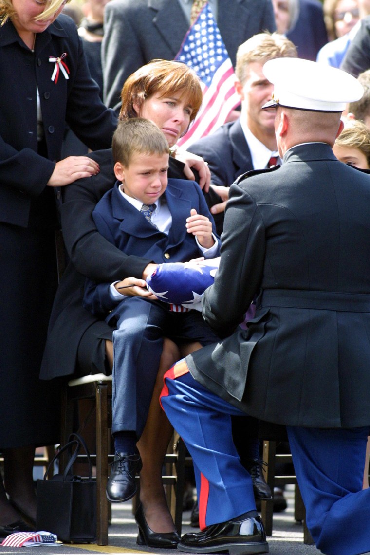 Miriam Horrocks, seated, with her son, Michael, 6, on her lap, is presented with the U.S. Flag by a U.S. Marine Corp honor guard following a funeral mass 17 September 2001 in Media, PA, for her late husband Michael Horrocks 38, who was killed 11 September when the hijacked United Airlines flight 175 that he was co-piloting crashed into the south tower of the World Trade Center in New York City.  Partially visable at far right is Horrocks' daughter, Christa, 9.    AFP PHOTO/ TOM MIHALEK