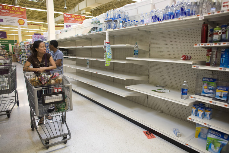 Image: A shopper passes by empty shelves while looking for bottled water at a Stop and Shop at Rockaway Beach in New York