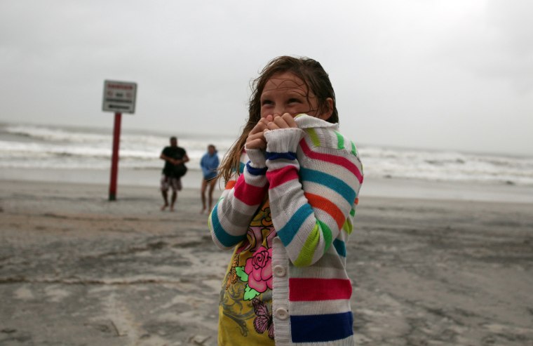Image: Rhiannon Shaw, 9, tries to stay warm while checking out the beach with friends as Hurricane Irene passes through Wrightsville Beach, N.C.