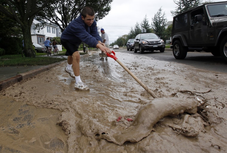 Image: Ken Smith clears the street in front of his family's house after Tropical Storm Irene hit the Rockaway beach section of Queens
