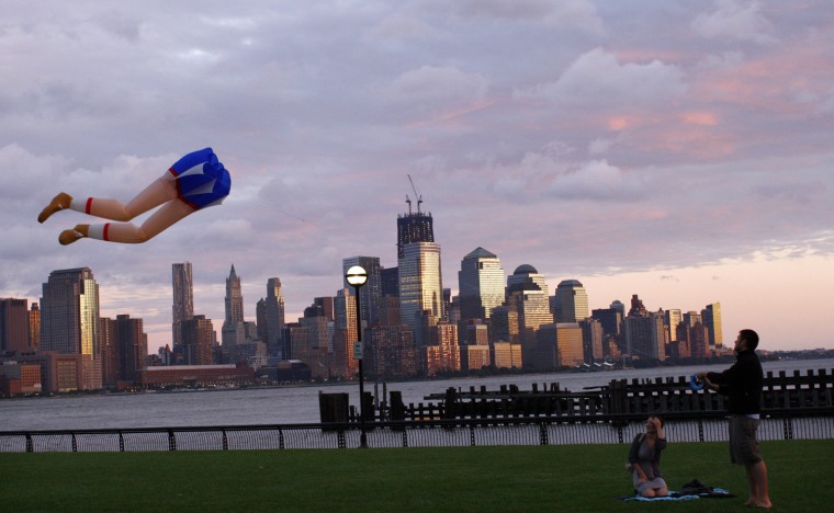 Image: With the skyline of New York in the background, people fly a kite along Hudson river after the pass of Hurricane Irene at Hoboken in New Jersey