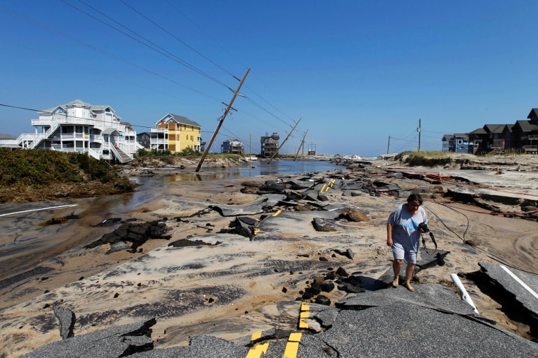 Image: Residents walk along Highway 12, the main road that connects Cape Hatteras National Seashore to the main land was destroyed by Hurricane Irene in Rodanthe