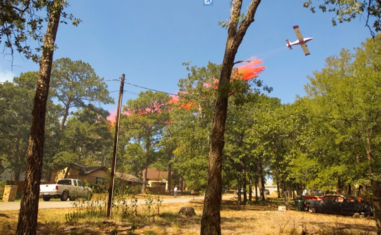 A plane drops fire retardant on a house in Bastrop's Tahitian Village neighborhood on Monday Sept. 5, 2011.
