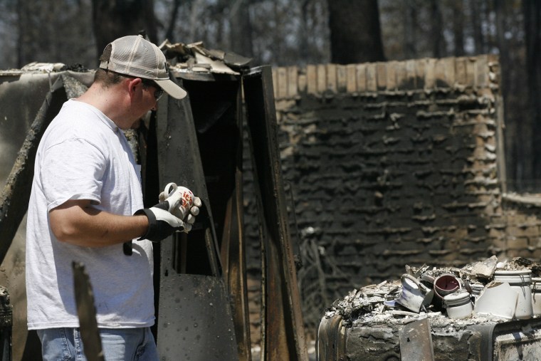 Image: A man looks through the debris of his home after it was destroyed by fire as wildfires burn out of control near Bastrop, Texas
