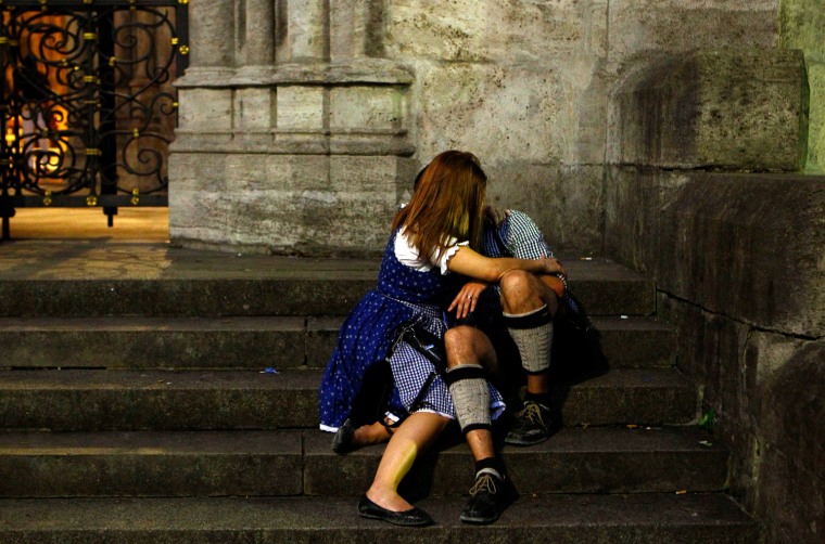 Image: Revellers wearing traditional Bavarian clothes hug on the stairs of the St. Peter and Paul church after leaving the Munich Oktoberfest, in Munich