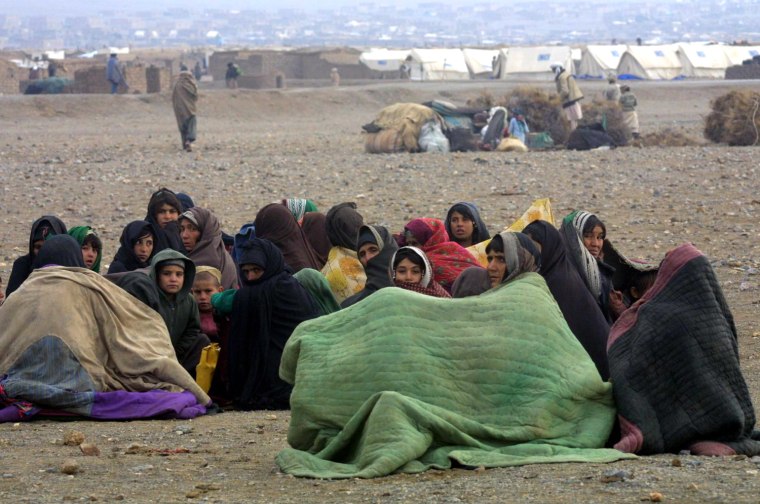 Afghan refugees keep themselves warm under wool blankets as they live homeless near the Maslakh refugee camp, west of Herat in western Afghanistan, 30 November 2001. They live on the ground without tents due to lack of space for them at the camp, where more than 200,000 are crammed and many have died from cold weather, hunger and illness.   AFP PHOTO/Behrouz MEHRI