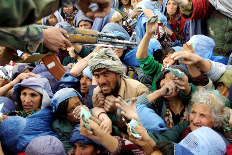 An Afghan northern alliance soldier tries to keep a crowd of desperate Afghans from crowding him, during a chaotic day of food distribution on the grounds of a high school, sponsored by World Food Program, and assisted by local authorities, in the Afghan capital Kabul, Monday, Dec. 10, 2001. As hunger grows in Afghanistan with the onset of winter, World Food Program plans to supply wheat to 1.3 million people over the next eight days. (AP Photo/Brennan Linsley)
