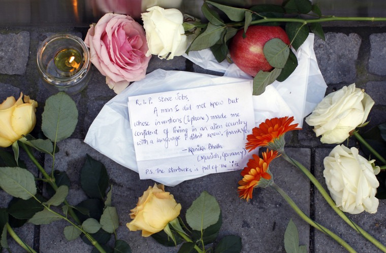 Image: Flowers candles and apple are placed in front of Apple store in Munich