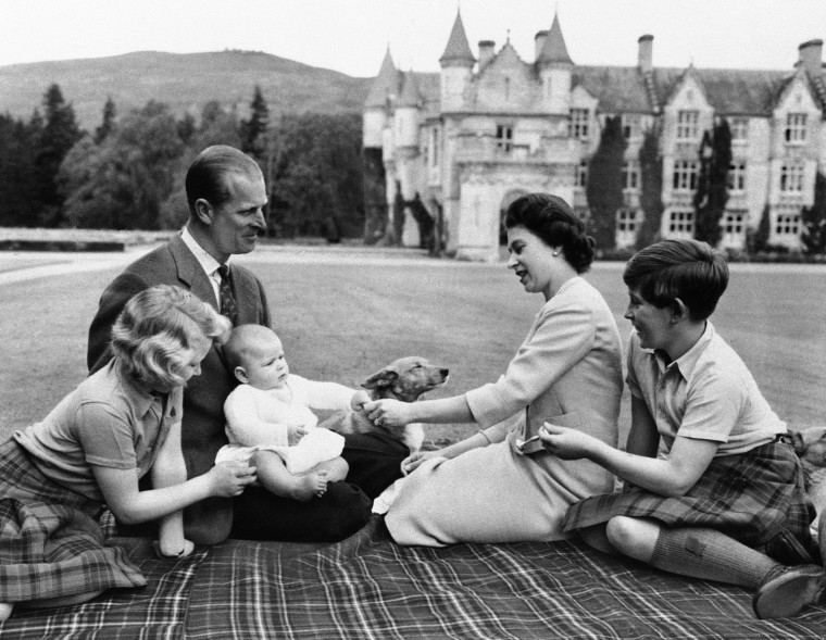 Britain's Royal family sits on blanket on the grounds of Balmoral Castle, Scotland, Sept. 8, 1960, during current holiday. Prince Andrew, in lap of his father, Prince Philip, reaches for trinket presented by his mother, Queen Elizabeth II, Princess Anne and Prince Charles try to catch the baby's attention. (AP Photo)