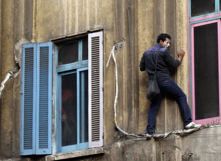 Image: A protester climbs a burned building to rescue residents trapped by fire, during clashes with police in Cairo