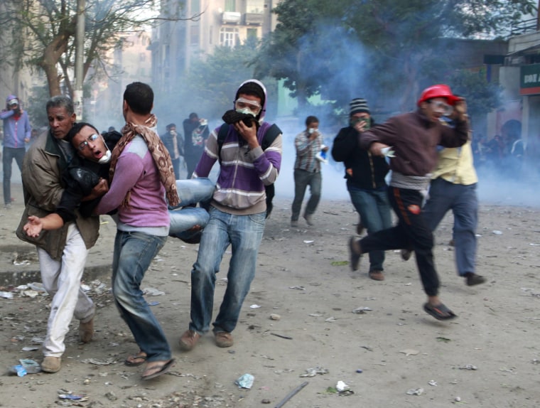 Image: Protesters help their fellow protester, who is affected by tear gas, during clashes with riot police near Tahrir Square in Cairo