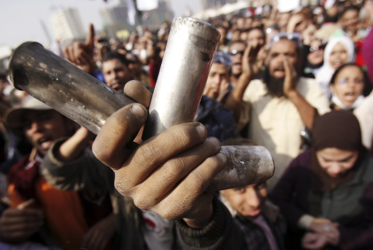 Image: A protester displays empty tear gas canisters during clashes with riot police at Tahrir Square in Cairo
