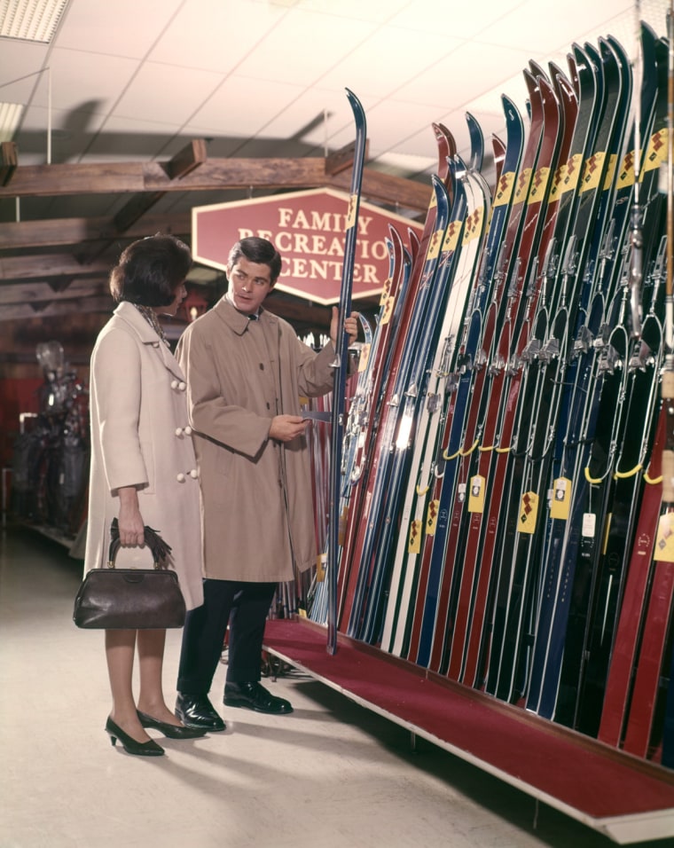 1960s COUPLE LOOKING AT SKIS IN SPORTS DEPARTMENT STORE LIFESTYLE VACATION MAN WOMAN. H. ARMSTRONG ROBERTS/CLASSICSTOCK/Everett Collection (ks3565)