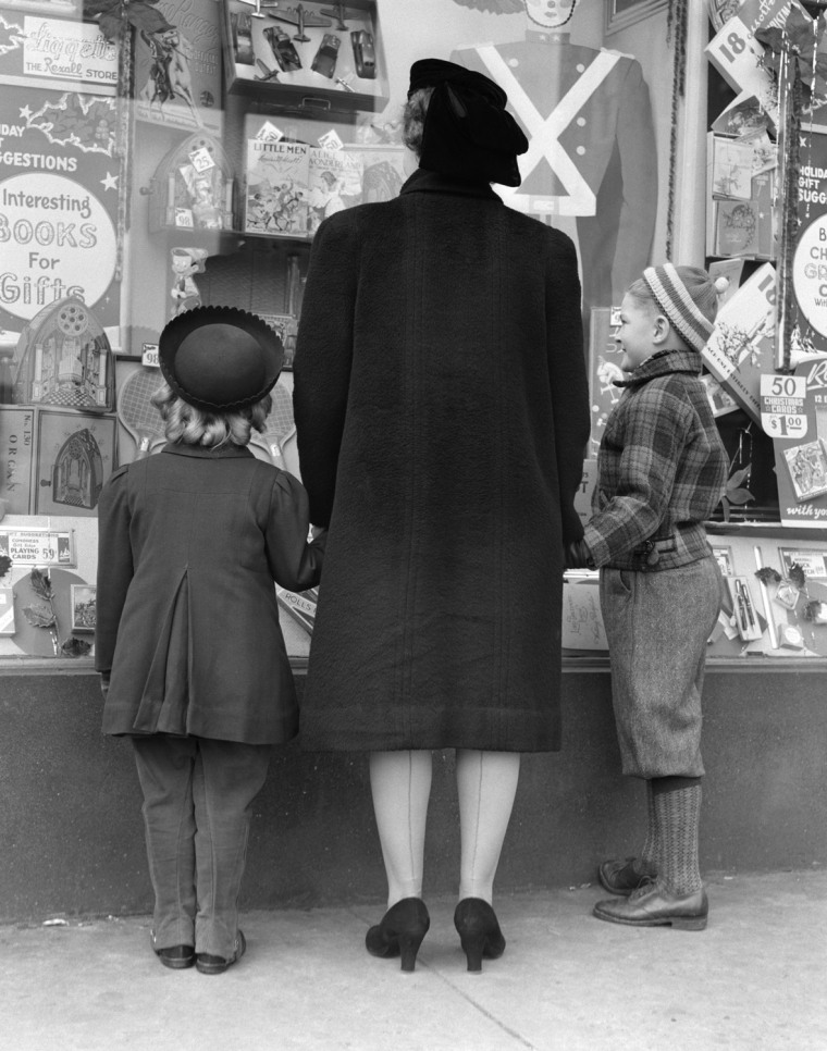 1930s VIEW OF BACKS OF MOTHER DAUGHTER AND SON WINDOW SHOPPING. H. ARMSTRONG ROBERTS/CLASSICSTOCK/Everett Collection (x924)