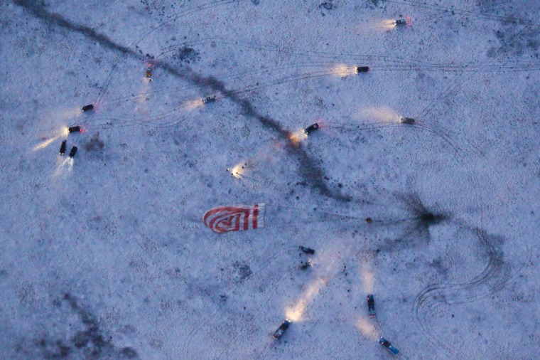 Image: An aerial view shows vehicles with their headlights on converging on the Soyuz spacecraft carrying ISS crew members after it landed near Arkalyk