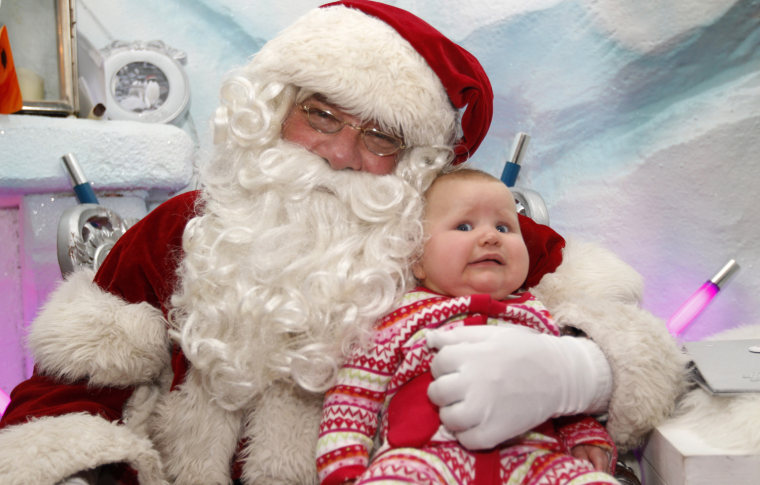 Image: Actor Warren, who has been playing Santa for the past ten years, holds seven-month-old Olivia Ruch at Santa's Grotto in Selfridges department store in London