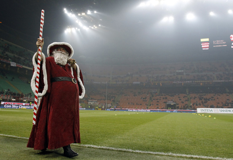 Image: Man dressed in a Santa Claus costume stands on the field before the start of the Italian Serie A soccer match between AC Milan and Chievo in Milan