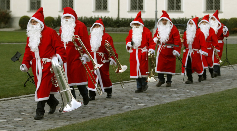 Image: Band members dressed in Santa Claus costumes make their way to perform in St. Gallen